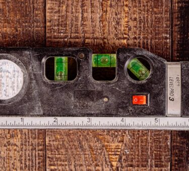 Combination laser level with bubble vials and a built-in tape measure on a wooden workbench