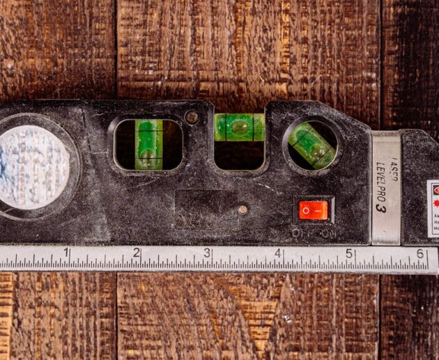 Combination laser level with bubble vials and a built-in tape measure on a wooden workbench