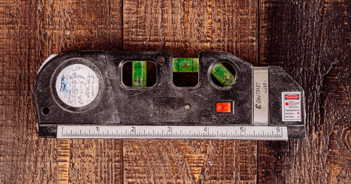 Combination laser level with bubble vials and a built-in tape measure on a wooden workbench