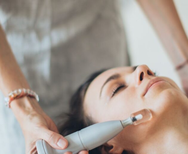 Handheld facial toning device being used along a woman's cheek during a treatment