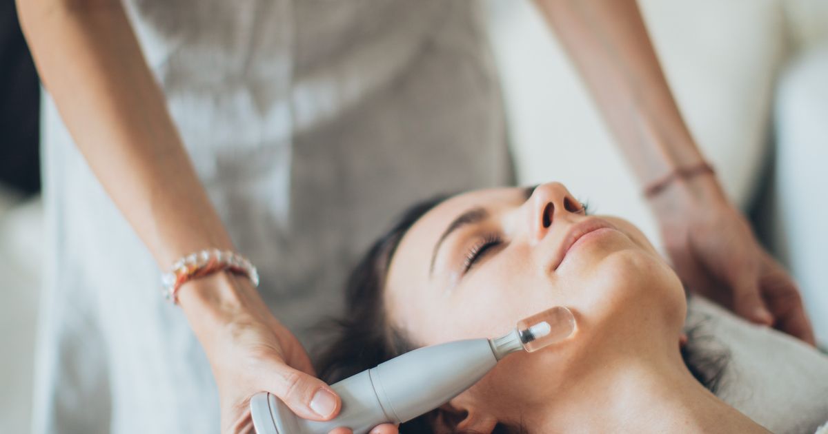 Handheld facial toning device being used along a woman's cheek during a treatment