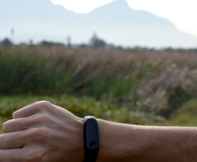 Man checking a black fitness tracker on his wrist outdoors