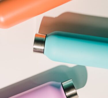 Three insulated stainless steel water bottles in different colors on a white surface