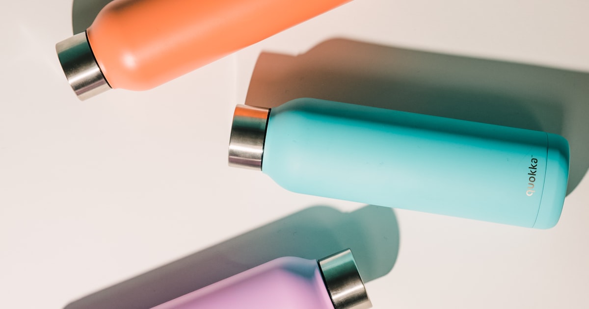 Three insulated stainless steel water bottles in different colors on a white surface