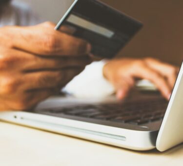 Person entering card details into a laptop while banking online at a desk