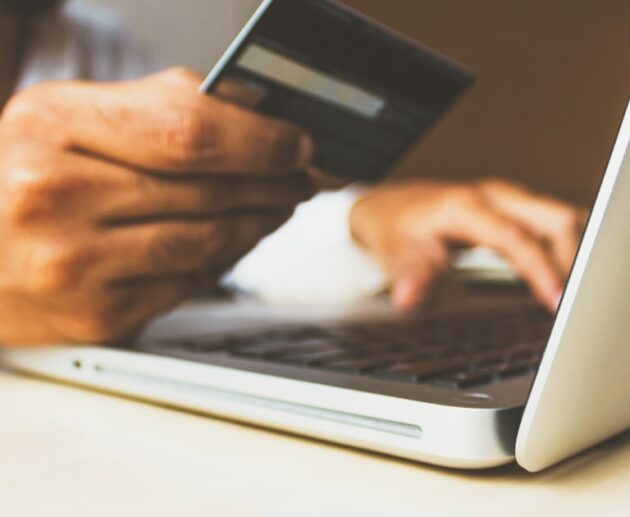 Person entering card details into a laptop while banking online at a desk
