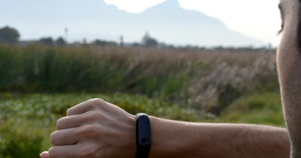 Man checking a black fitness tracker on his wrist outdoors