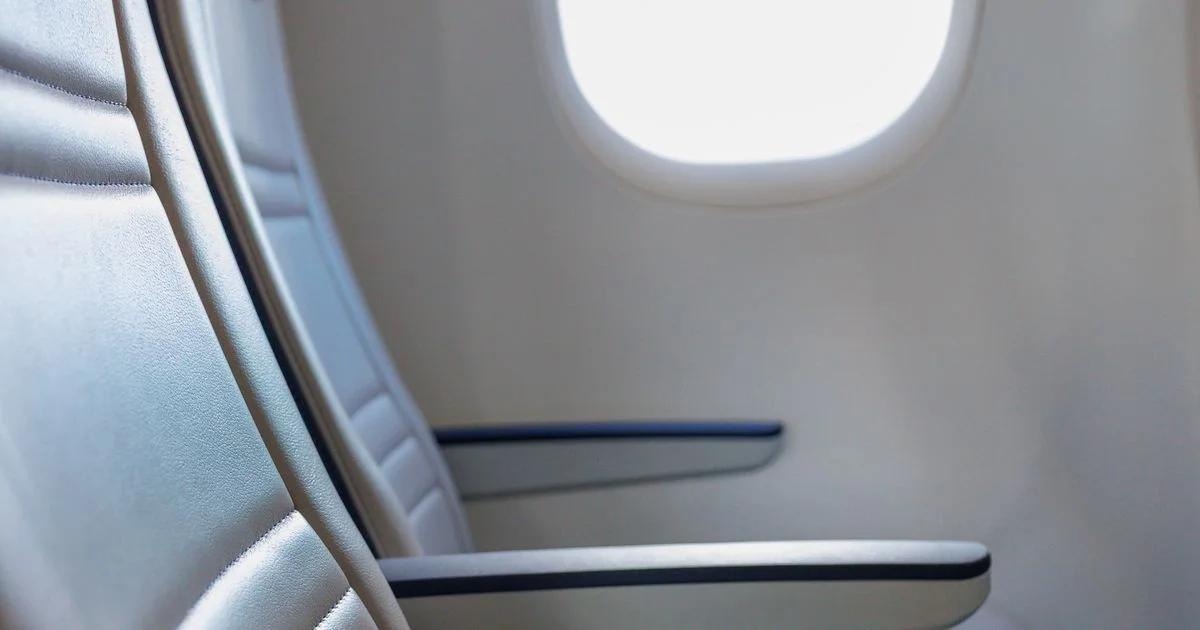An empty aircraft window seat and cabin window, the long-flight situation that decides AirPods Max for travel