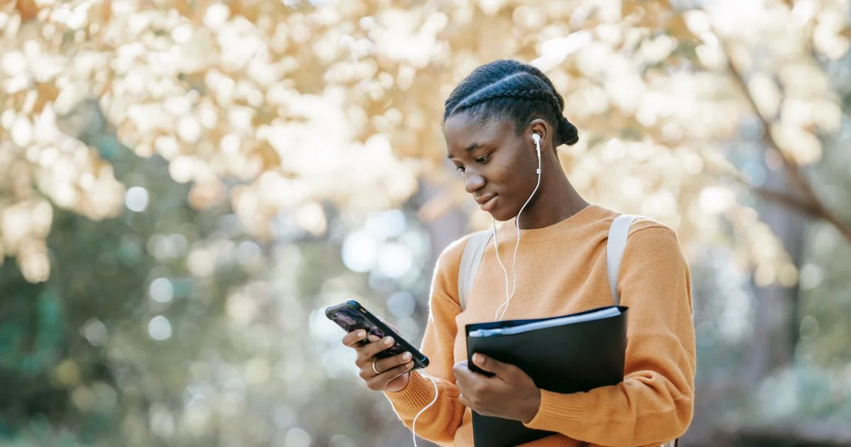 A student walks with earbuds and a phone, the everyday way people use the best language learning app for beginners