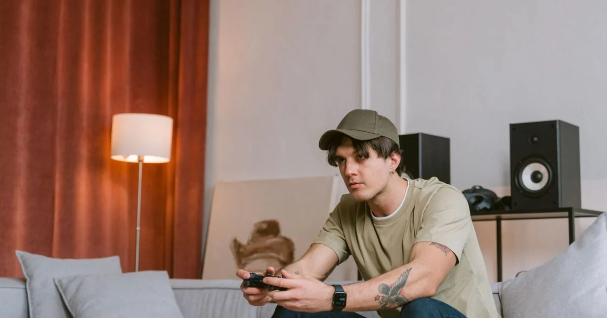 A man playing a console game on a living room sofa, the couch setup the best smart AR glasses for gaming are bought to replace