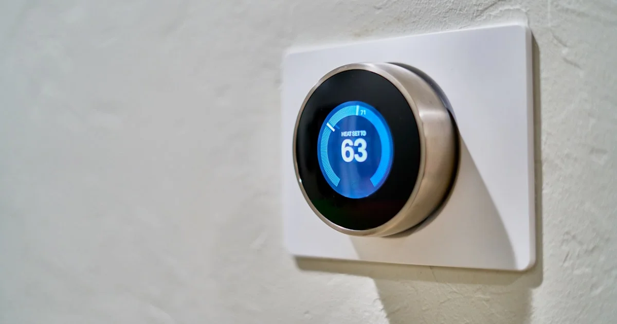 Round smart thermostat mounted on a wall displaying 63 degrees, the kind used for energy savings