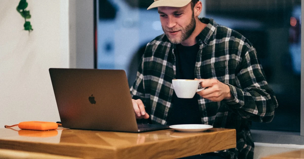 Man working on a laptop in a coffee shop, the setting where the best VPN for public wifi security matters most