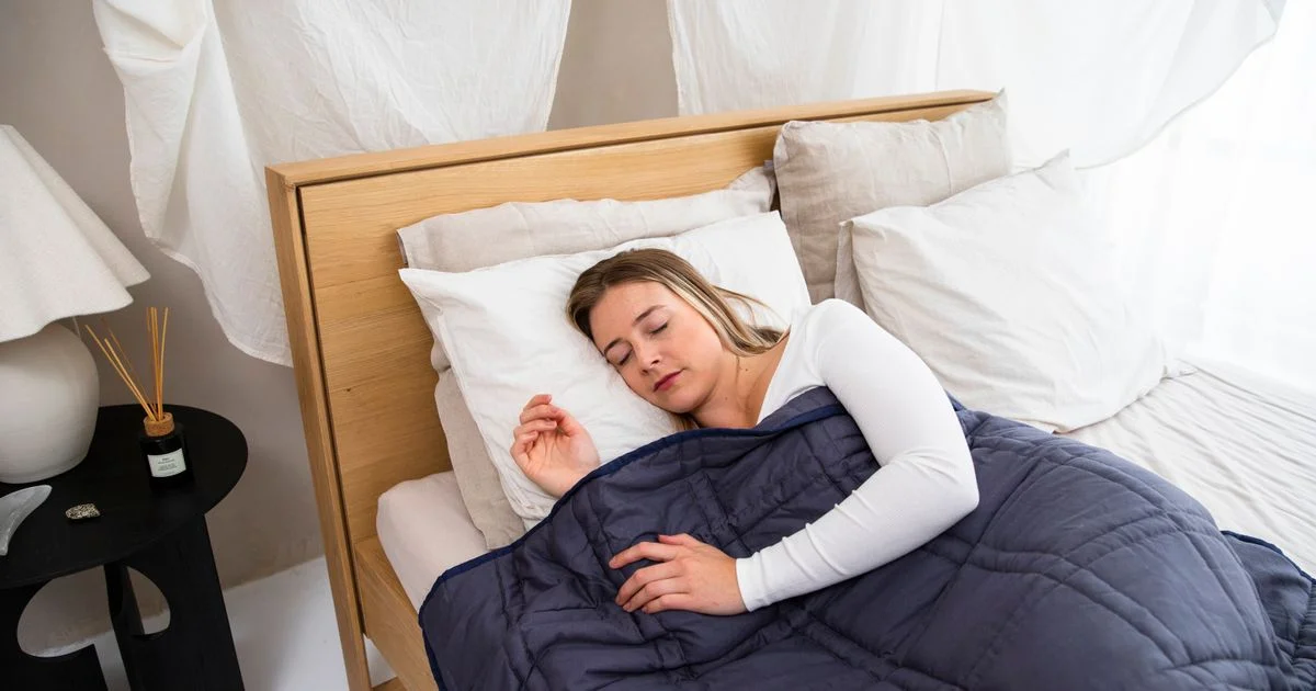 Woman asleep under a navy quilted blanket, showing what the best weighted blanket for anxiety looks like in everyday use