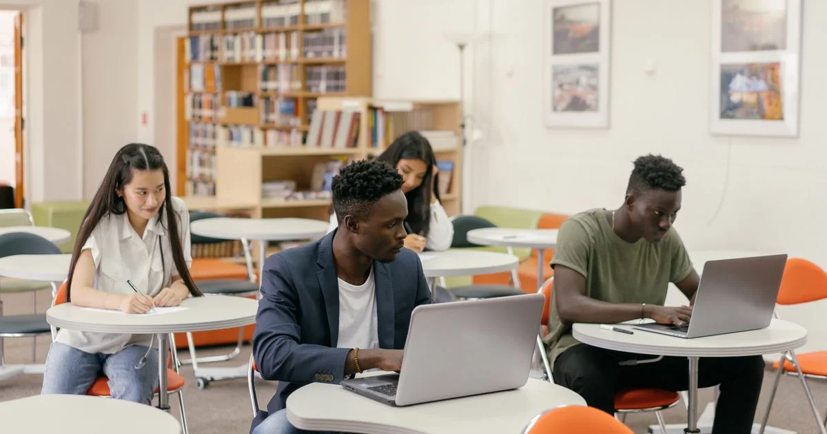 Students working at tables in a campus library, the everyday setting for a budget laptop for students