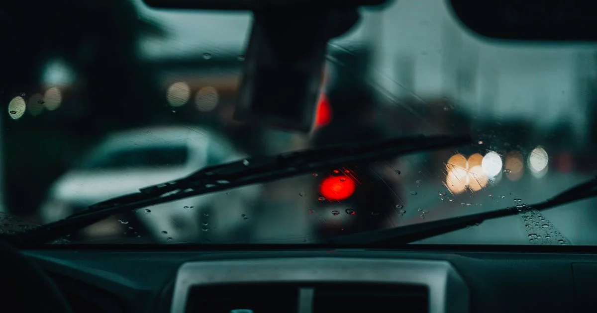 Rain on a windshield, wipers mid-sweep and brake lights ahead, the conditions a dash cam for cars records most often