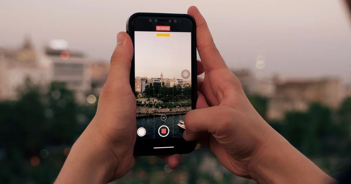 Hands holding a phone photographing a city at sunset, the kind of shot that fills free cloud storage for photos