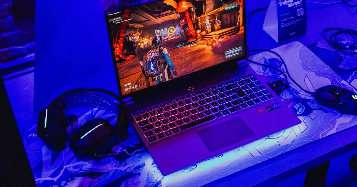A gaming laptop running a game on a desk with a headset and mouse beside it