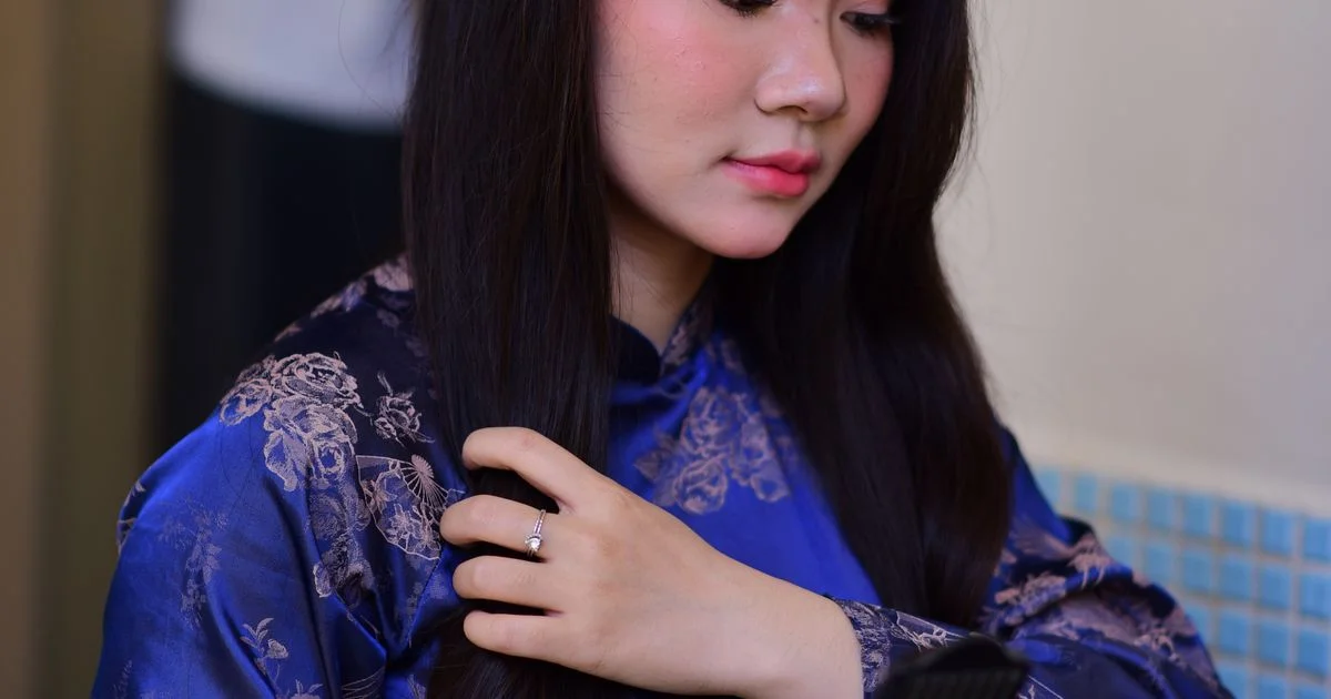 Woman using a hair straightener on her own thick dark hair at home