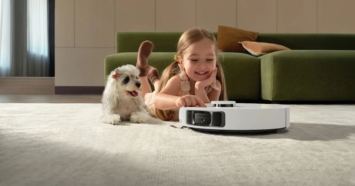 A robot vacuum for pet hair running across a living room rug while a small dog rests nearby