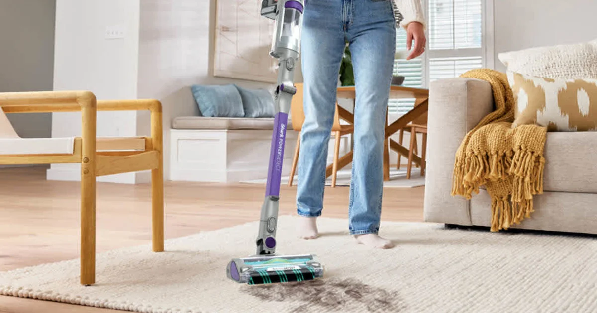 A Shark cordless stick vacuum cleaner for pet hair being pushed across a living room rug