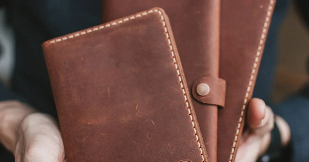 Hands holding two plain leather wallets, the everyday object a smart wallet for men has to replace