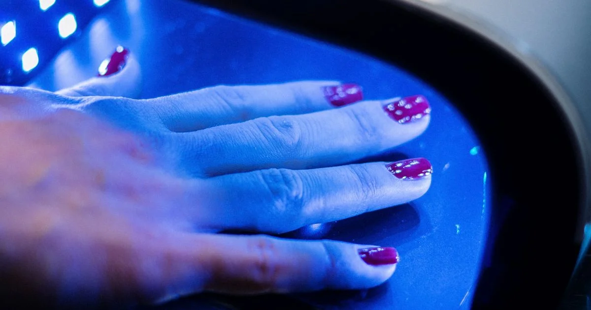 A hand curing under a UV nail lamp for gel manicures, with the whole back of the hand inside the light