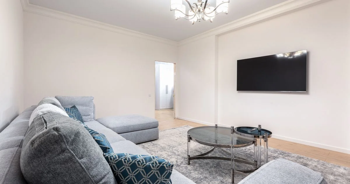 Grey sectional couch facing a wall-mounted screen with a blank display, the seating distance that decides a smart TV for movie nights