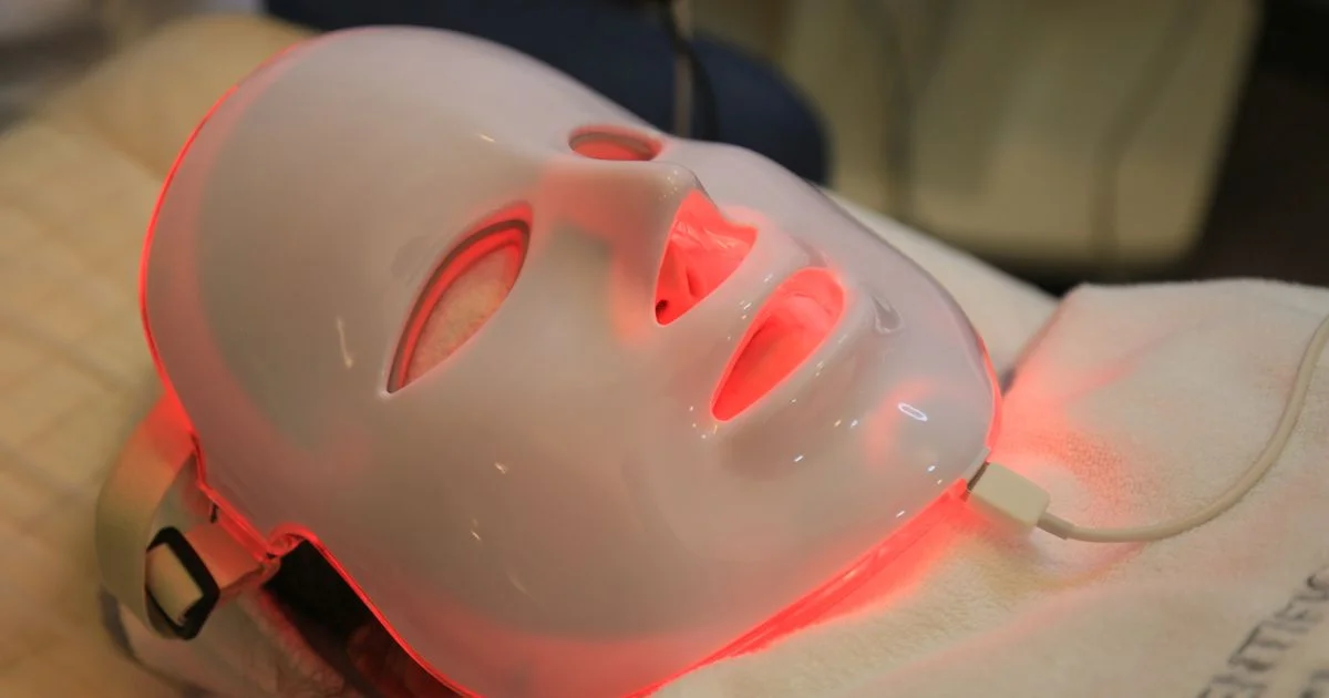 An illuminated LED face mask resting on a treatment pillow, the device format behind a Theraface LED mask for acne routine